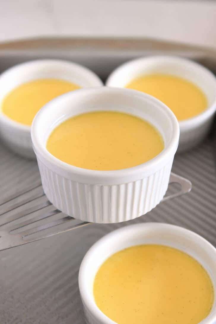 Using spatula to remove baked creme brulee in ramekins from metal baking dish.