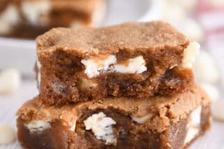 Two squares of white chocolate gingerbread blondie bars stacked with bite taken out of bottom bar.