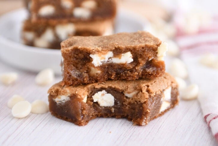 Two squares of white chocolate gingerbread blondie bars stacked with bite taken out of bottom bar.