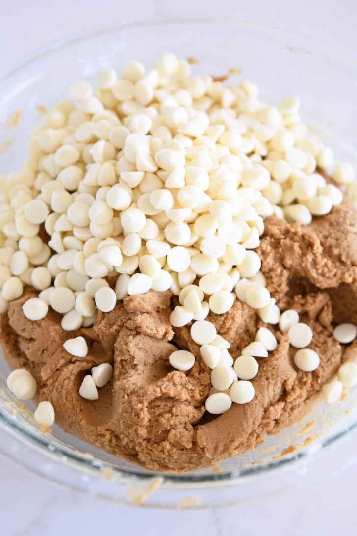 Glass bowl with gingerbread cookie batter and white chocolate chips.