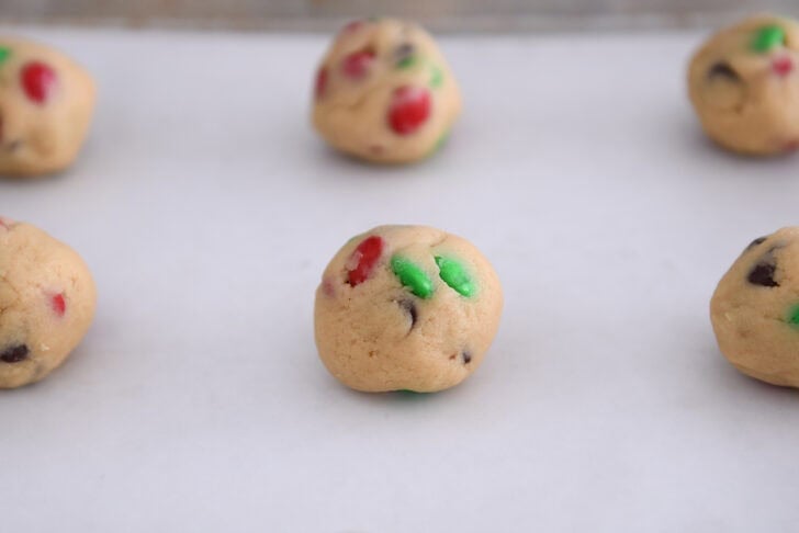 Sheet pan with cookie dough balls on parchment paper.