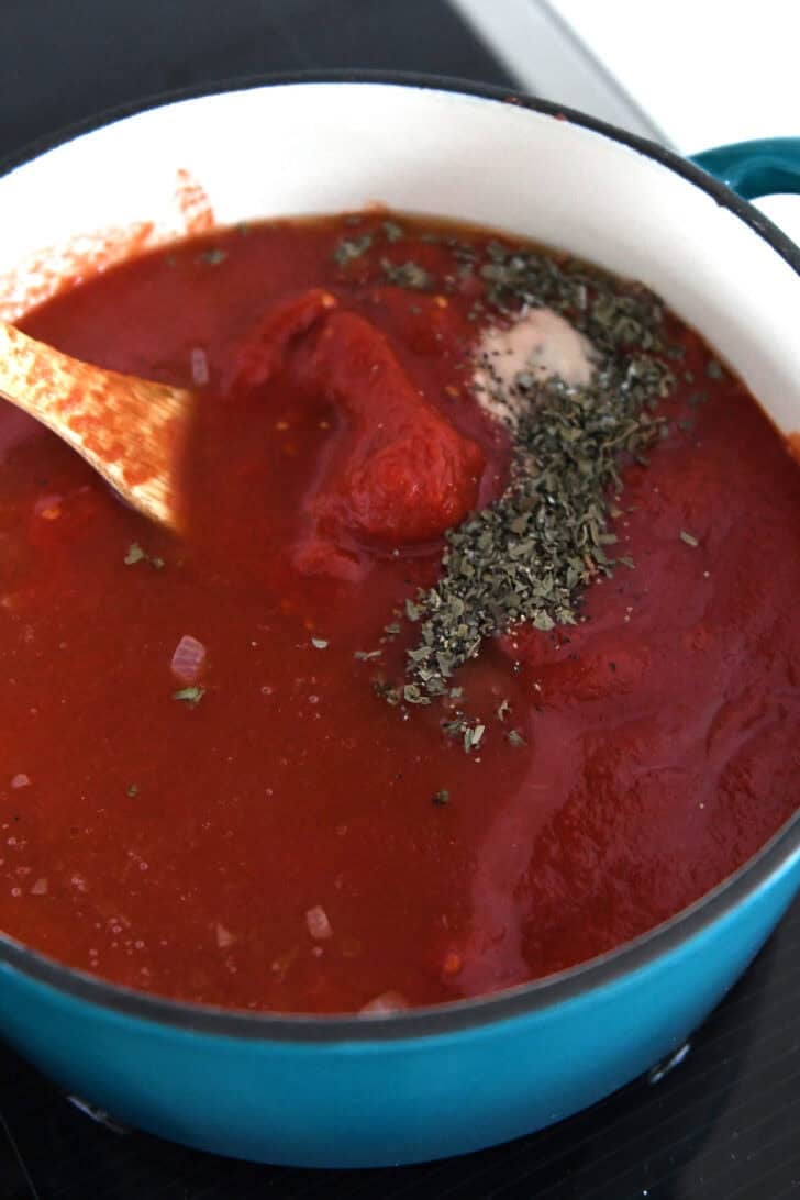 Cast iron enamel pot with canned tomatoes, dried basil, baking soda and broth.