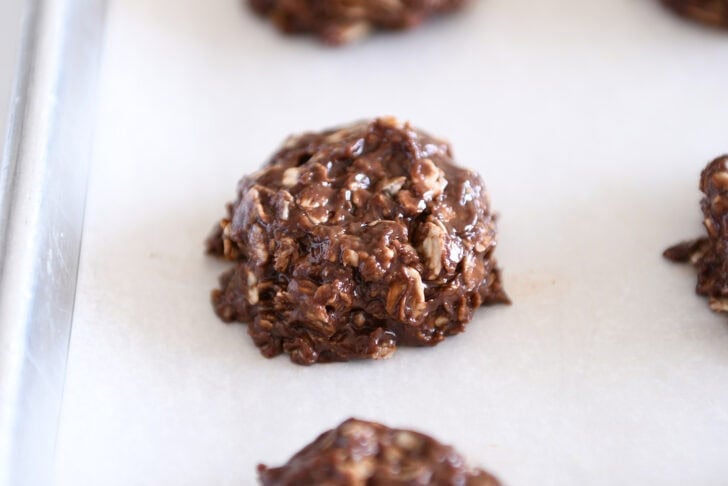 Flattened mound of no-bake cookie dough on parchment lined baking sheet.