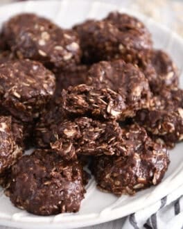 Stack of chocolate no-bake cookies on white plate with one cookie broken in half.