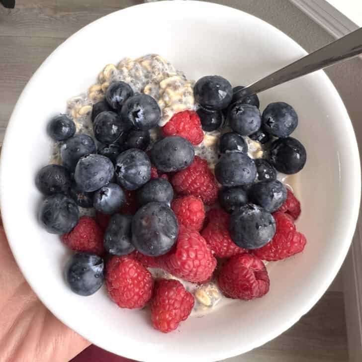White bowl with chia oats, raspberries and blueberries.