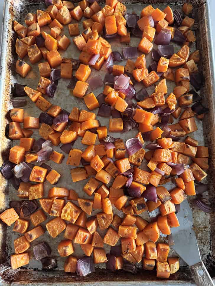 Sheet pan with roasted sweet potatoes and red onions.