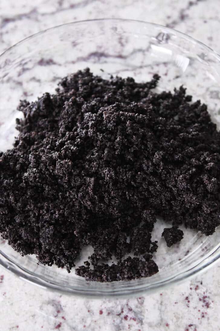 Top down view of a glass pie dish with Oreo crumbles ready to be made into a crust.