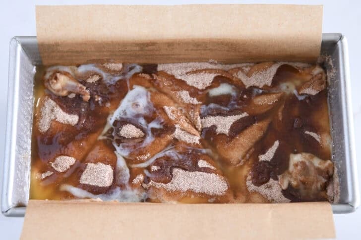 Bread pan with bread dough, cinnamon swirl and melted butter.