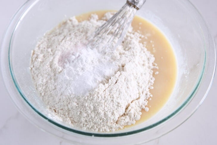 Top the quickbread dough in a glass bowl with the flour, baking soda, baking powder, and salt.
