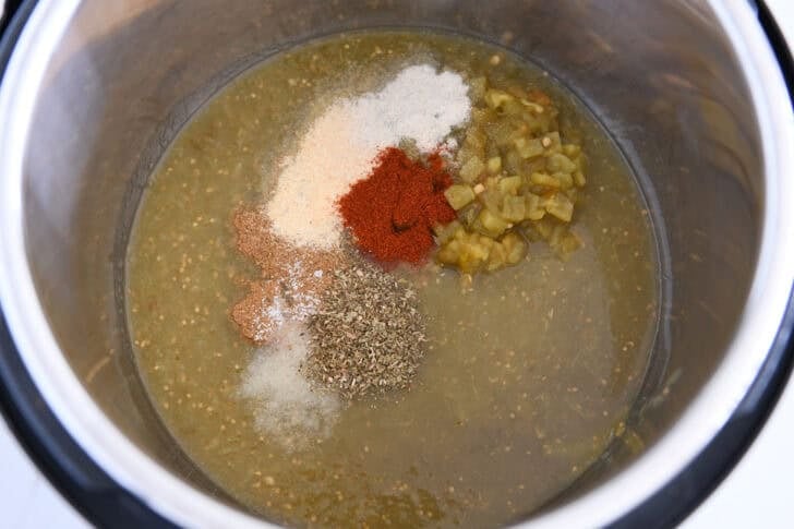 Salsa verde, green peppers, oregano, smoked paprika, onion powder, garlic powder, and cumin in the Instant Pot.