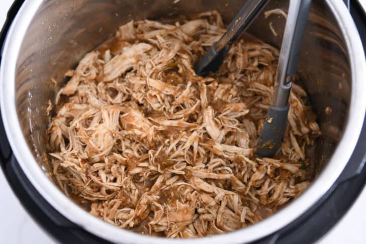 Add shredded salsa verde chicken and tongs to the Instant Pot.