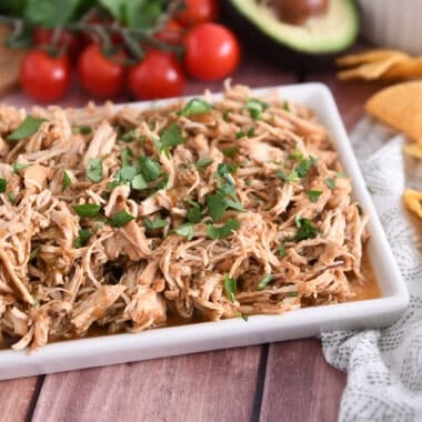 Shredded salsa verde chicken on white tray.