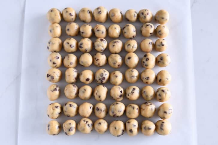 Makes 64 mini chocolate chip cookie dough balls on white parchment paper.