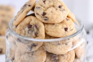 A glass jar with mini chocolate chips at the bottom and filled with mini chocolate chip cookies.