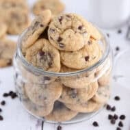 A glass jar with mini chocolate chips at the bottom and filled with mini chocolate chip cookies.