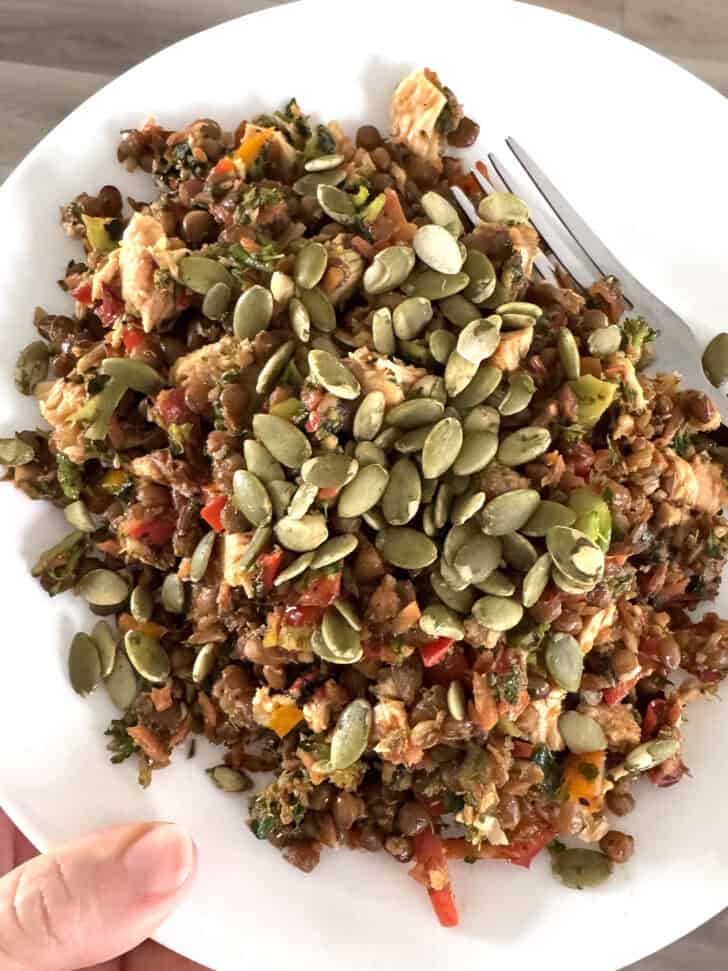 Plate of sauteed broccoli, peppers, tuna and pumpkin seeds.