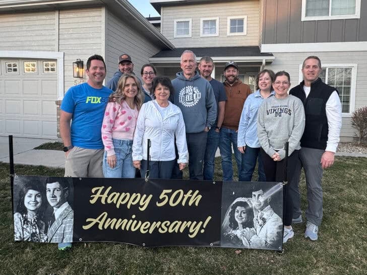 Parents and adult siblings in front of sign that reads Happy 50th Anniversary!
