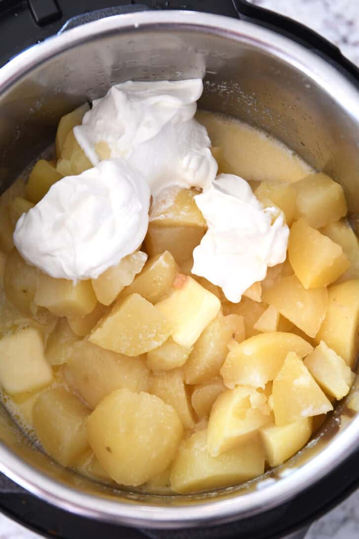 Top down view of an Instant Pot with cooked potatoes and sour cream.