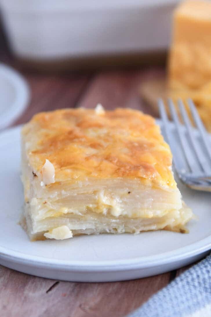 Square of baked au gratin potatoes on gray plate.