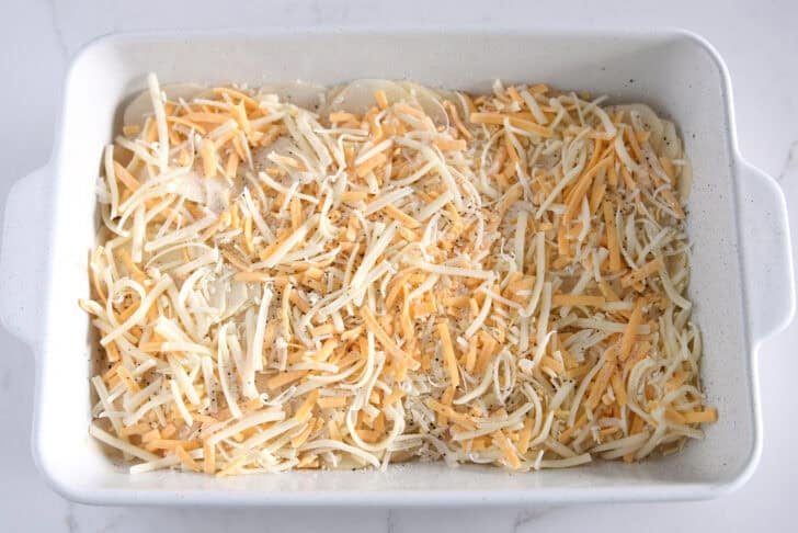Shredded cheese layered on top of sliced potatoes.