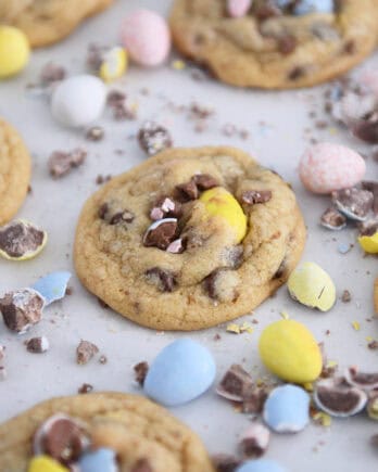 Baked cookies on parchment paper with crushed and whole cadbury eggs scattered around.