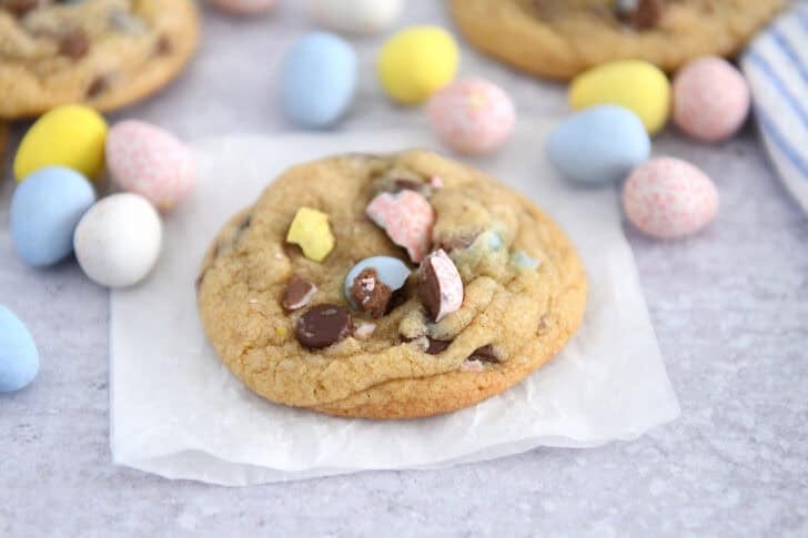 Baked cadbury egg chocolate chip cookie on parchment paper.