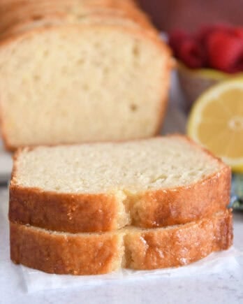 Two slices of lemon quick bread stacked on parchment paper.