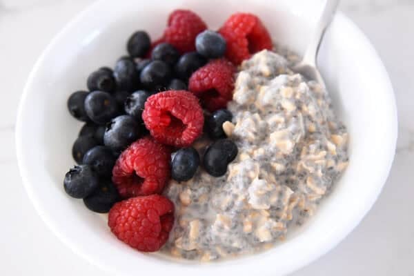 White bowl with chia oats, blueberries, and raspberries.