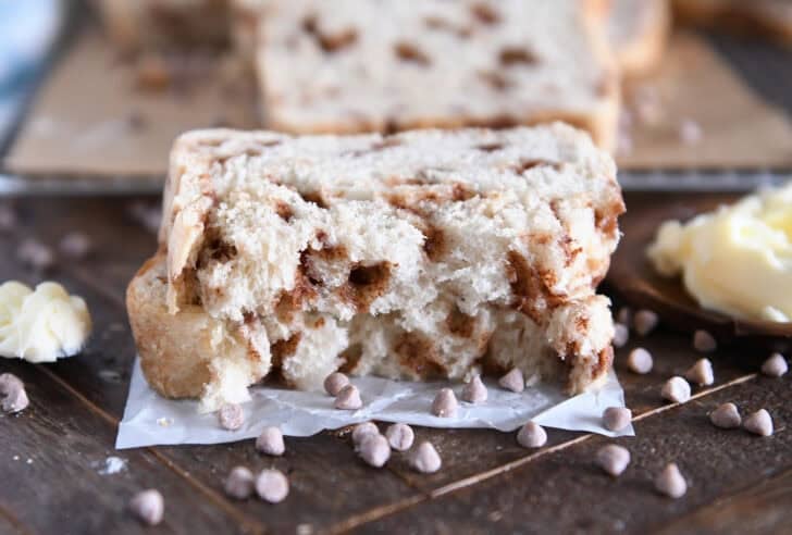 Two halves of cinnamon burst bread stacked on white parchment paper.