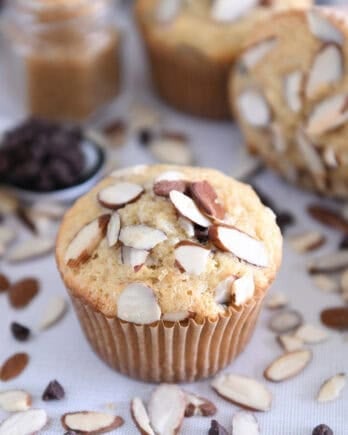 Almond coconut chocolate chip muffin on brown paper muffin liner.