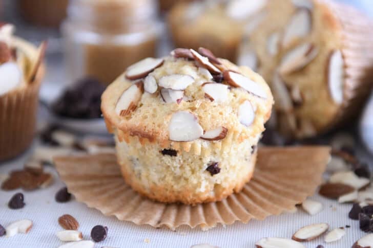 Unwrapped almond coconut chocolate chip muffins in brown paper muffin liners.