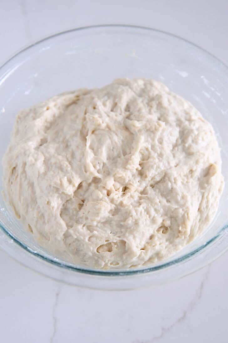 Shaggy mixed focaccia dough in a glass bowl.