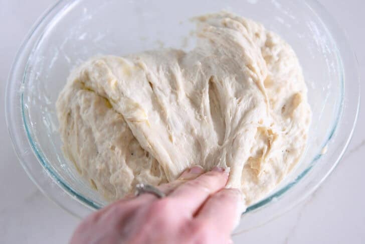 Spread and fold the focaccia dough into a glass bowl.