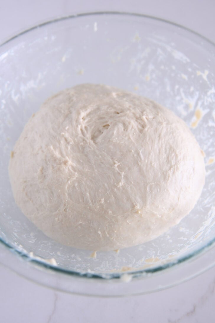 Focaccia dough in a glass bowl.