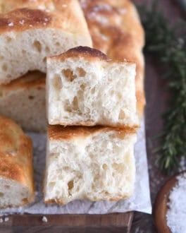 Two half pieces of fluffy focaccia on white parchment paper.