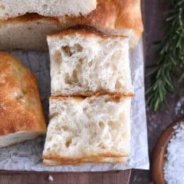 Two half pieces of fluffy focaccia on white parchment paper.