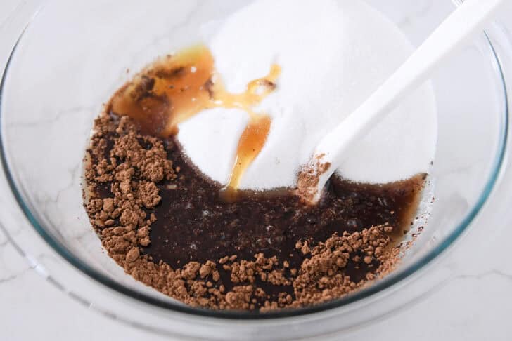 Glass bowl with cocoa powder, honey, sugar and water.