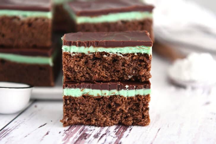 Two half chocolate mint brownies stacked on top of each other.