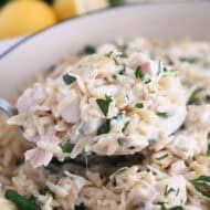 Serving spoon with scoop of creamy orzo, spinach and chicken.