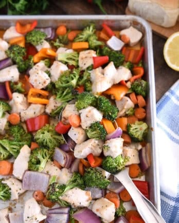 Top down view of serving spoon with cooke chicken, broccoli, carrots, bell peppers and red onions.