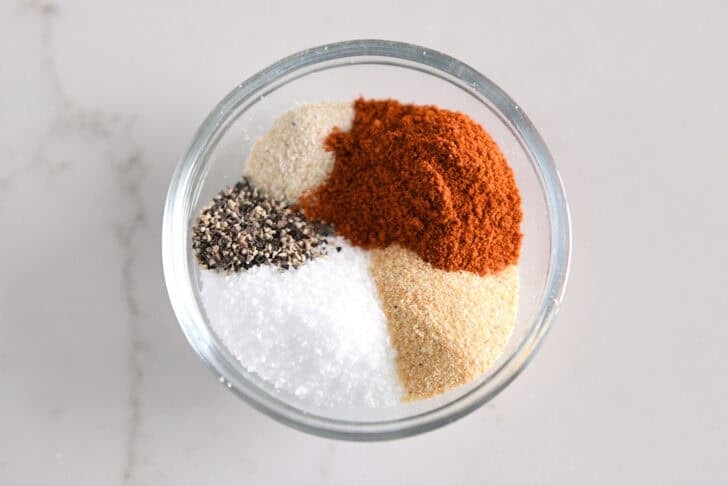 Put pepper, salt, onion powder, garlic powder, and paprika in a glass bowl.