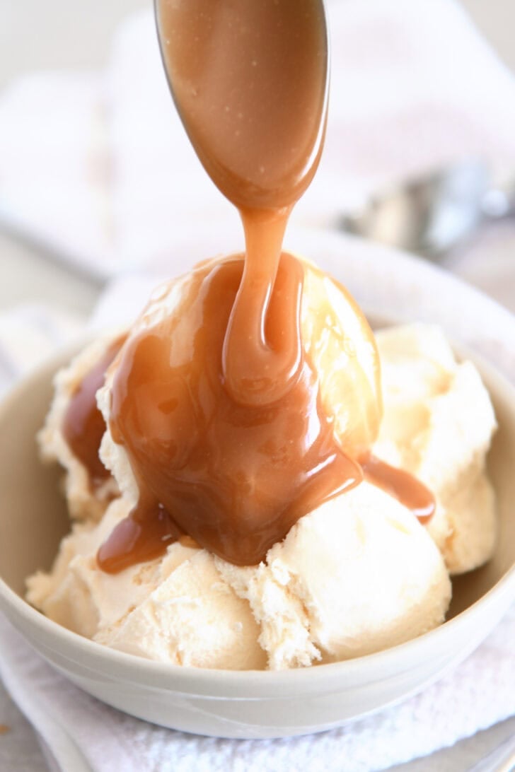 Drizzling caramel sauce over vanilla ice cream.