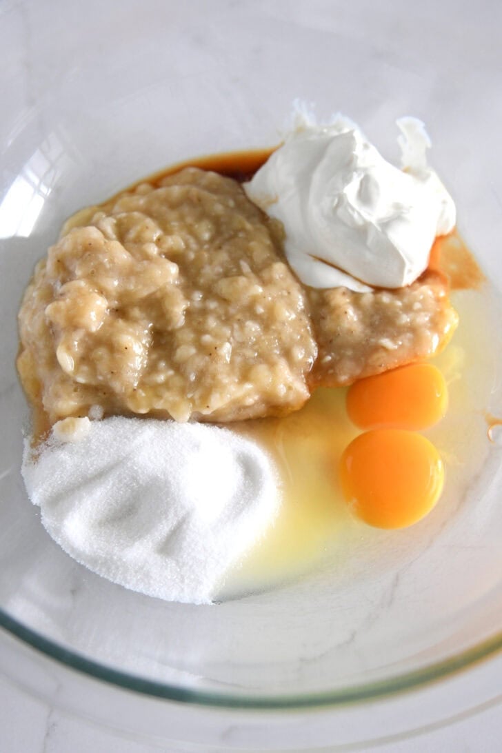 Glass bowl with mashed bananas, sugar, eggs and sour cream.