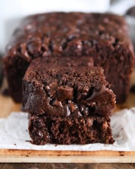 Two half slices of chocolate banana bread stacked on white parchment paper.