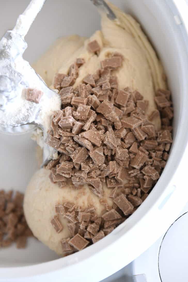 Dough in white bosch mixer dotted with homemade cinnamon bits.