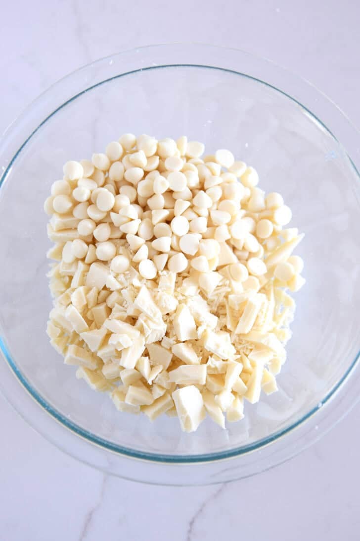 Glass bowl with chopped white chocolate and white chocolate chips.
