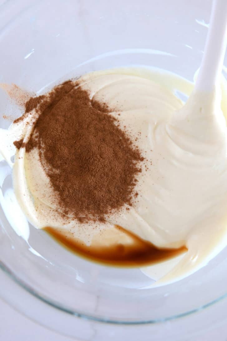 Glass bowl with melted white chocolate, vanilla, and ground cinnamon.