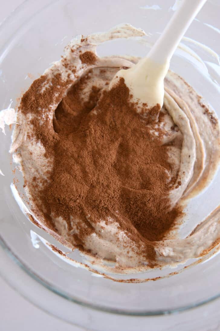 Glass bowl with melted white chocolate and ground cinnamon.