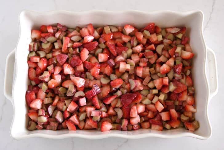 White pan with cut up strawberries and sliced rhubarb.