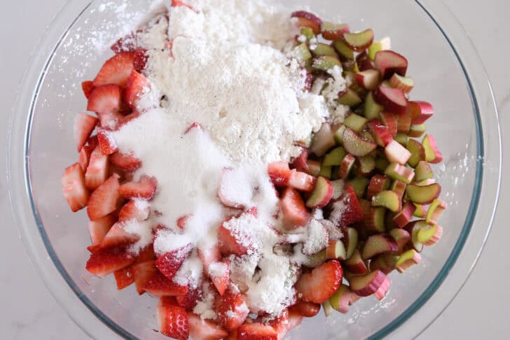 Glass bowl with strawberries, rhubarb, sugar, and cornstarch.